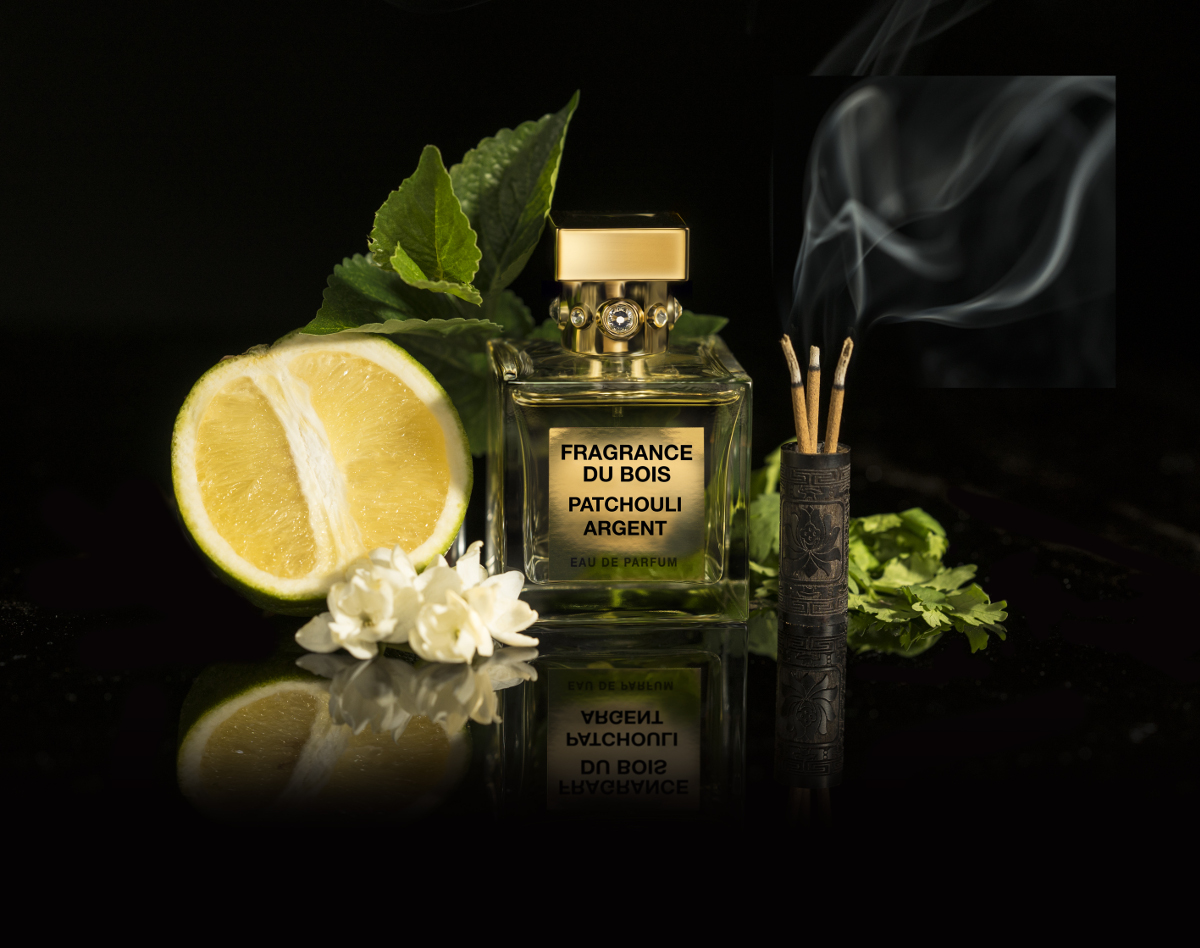 A bottle of Patchouli Argent next to a lemon and a burning incense stick